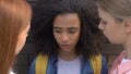 Classmates bullying biracial girl at wall, psychological attack, intimidation