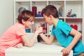 Classmates competing in arm wrestling during the break. Happy friends playing arm wrestle looking at each other