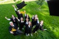 Classmates in graduation gowns throw their caps. View from above.