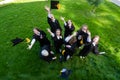 Classmates in graduation gowns throw their caps. View from above.