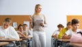 Classmates and female teacher working in groups to complete task during class