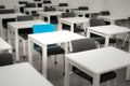 Classroom with black chairs and one blue chair. Hiring, vacant or choosing concept