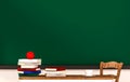 Classroom, books, apple, coffee cup, table, chair and green blackboard, with copy space, 3d rendered Royalty Free Stock Photo