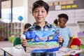 Classroom Portrait Of Proud Male Elementary School Pupil Holding Painting In Art Class At School