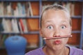 Classroom shenanigans. A cute young girl balancing her pencil on her lips and pulling a face.