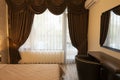 Classy bedroom interior design. Large bed. Room with brown color tone furniture. Windows with long curtains, drapery and sheers.