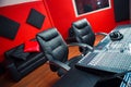 Classy professional recording studio setup, large desk with mixing console and two chairs, window for vocal booth, sofa