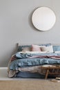 Classy mirror on grey wall in stylish bedroom interior with warm bed with blue, pastel pink and beige bedding Royalty Free Stock Photo