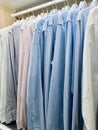 Classy, stylish, colorful men's formal long sleeve shirts neatly arranged and organized in a row on a clothes rack