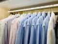 Classy, stylish, colorful men's formal long sleeve shirts neatly arranged and organized in a row on a clothes rack