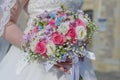 Classy young bride at the wedding ceremony with focus on the hand holding a floral arrangement