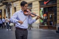 Classy young violinist playing on a street