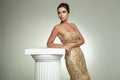 Classy young woman in long elegant dress leans on column