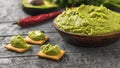 Clay bowl with fresh guacamole, tomatoes, lemon, chips, avocado and garlic on wooden table. Diet vegetarian Mexican food avocado. Royalty Free Stock Photo
