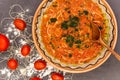 Clay bowl with traditional dish consist of tomatoes with grain noodles on slate and wooden spoon and ingredients near