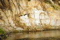 Clay cliff near the water of the river with erosional types of relief and protruding roots.