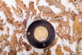 a clay cup with freshly brewed coffee and beautiful autumn oak leaves and acorns in a chaotic order on a white slate or Royalty Free Stock Photo