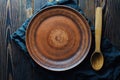 Clay empty plate and wooden spoon on wooden background top view