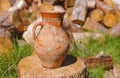 Clay jug with ancient ornamental pattern standing on a wooden log