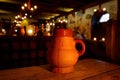 Clay jug with beer on a wooden table in a medieval tavern.