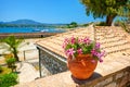 Clay jug with magenta flowers on stone wall. Classical yachts in Mediterranean sea. Kerkyra castle. Greece holidays vacations tour Royalty Free Stock Photo