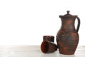Clay jug and mugs on white wooden table Royalty Free Stock Photo