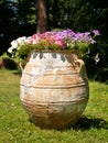 Clay jug, very old, filled with beautiful flowers. Royalty Free Stock Photo