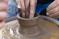 Clay modeling, women`s wet and dirty hands make a hole in the pot of clay on the Potter`s wheel manual control on the master class Royalty Free Stock Photo