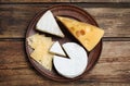 Clay plate with different cheeses on table, top view