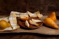 Clay plate with half and slices of pears and whole fruits on wooden background with yellow kitchen towel Royalty Free Stock Photo