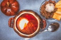 Clay pot with red soup and sour cream on a linen napkin