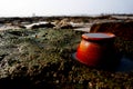 A clay pot on a rocky beach.