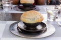 Clay pot under the bread lid hot vegetable soup served in a restaurant on silver plate. Royalty Free Stock Photo