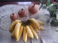 Clay pots, bananas and leaves compostion on white mat