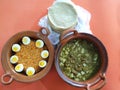 Clay pots filled with rice with boiled egg and pork rinds in green sauce, accompanied by corn tortillas