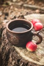 Clay Rural Cup with Hot Beverage and red apples on Wooden Stub.