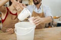 Dark-haired bearded potter pouring some clay substance