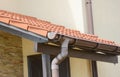 Clay tiled, ceramic tiled roof with a brown roof gutter system above the entrance door