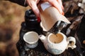 Clay white teapot with blue pattern and two pialam in the forest on the stump. The girl pours tea