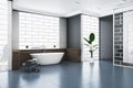 Clean bathroom interior with bathtub, abstract windows and reflections on concrete flooring.