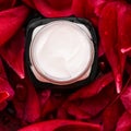 Sensitive skincare moisturizer cream on red flower petals and water background, natural science for skin Royalty Free Stock Photo