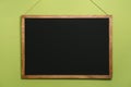 Clean black chalkboard hanging on light green wall Royalty Free Stock Photo