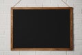 Clean black chalkboard hanging on white brick wall Royalty Free Stock Photo