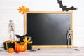 Clean blackboard with Halloween decorations against white brick wall. Halloween holiday background