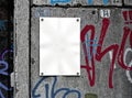 A clean blank poster placed on a graffiti-covered urban wall, offering a sharp contrast to the vibrant surroundings Royalty Free Stock Photo