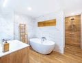 Clean bright bathroom interior with wooden floor, white toilet and marble tiles.