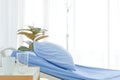 Clean and clear empty hospital near sunny window, blue bed linen with white curtain in ward room for background.