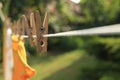 Clean clothes drying outdoors during sunny day, focus on laundry line with wooden clothespins Royalty Free Stock Photo