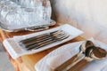 Clean cutlery: spoons, forks, knives in white stands and blurry tray with glasses stand on wooden shelf Royalty Free Stock Photo