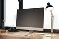 Clean designer desktop with empty computer monitor, lamp, supplies and other items. Window with city view in the background. Mock Royalty Free Stock Photo